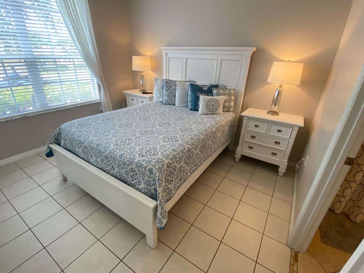 A bedroom with a bed, nightstands, and a window with blinds.