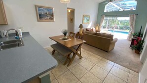 Et moderne køkken med spiseplads, en sofa og udsigt til en swimmingpool.