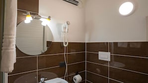 A bathroom with a round mirror, a white sink, a towel rack, a toilet paper holder, and a wall-mounted heater. - Hice Room (Catanzaro)