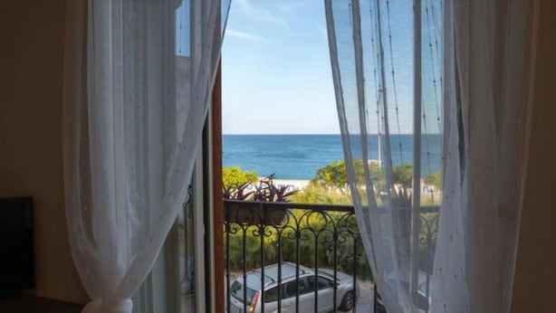 A balcony with a view of the sea, a car, and greenery. - Hice Room (Catanzaro)