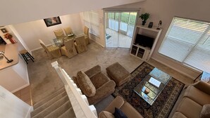 A spacious living area with a staircase, a dining set, and a TV. - The Solterra Sanctuary (Haines City)