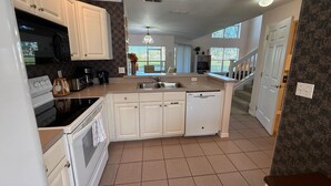 A kitchen with white cabinets, a black microwave, a coffee maker, and a dishwasher. - The Solterra Sanctuary (Haines City)