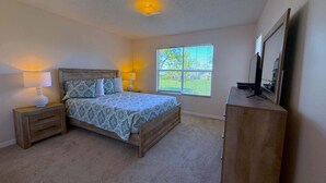 A bedroom with a bed, bedside lamps, a dresser, a window, and a ceiling light fixture. - The Solterra Sanctuary (Haines City)