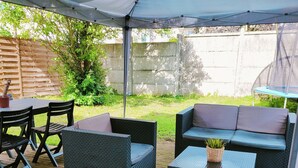 Une terrasse extérieure avec des meubles en osier, une table et un espace abrité.