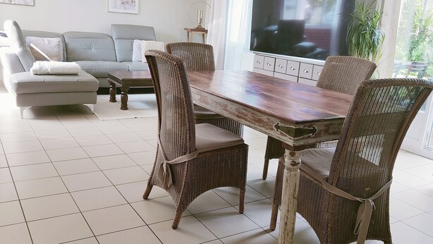 Un salon moderne comprenant une table à manger, des chaises en osier, un canapé et un téléviseur à écran plat.