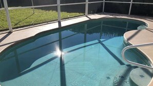 Ein klarer, runder Swimmingpool mit einer Metallleiter und einer Betonplattform.