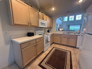A kitchen with wooden cabinets, a microwave, a stove, and a refrigerator.