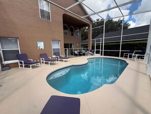 A swimming pool with lounge chairs and a covered area. - Golden Fairway Retreat (Haines City)