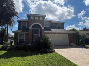 A two-story house with a garage, a driveway, and a well-maintained lawn. - Golden Fairway Retreat (Haines City)