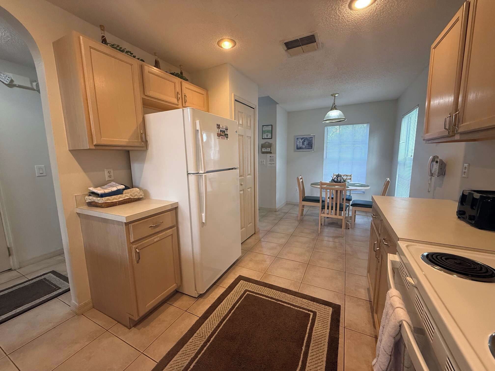 A compact kitchen with a refrigerator, stove, and dining table.