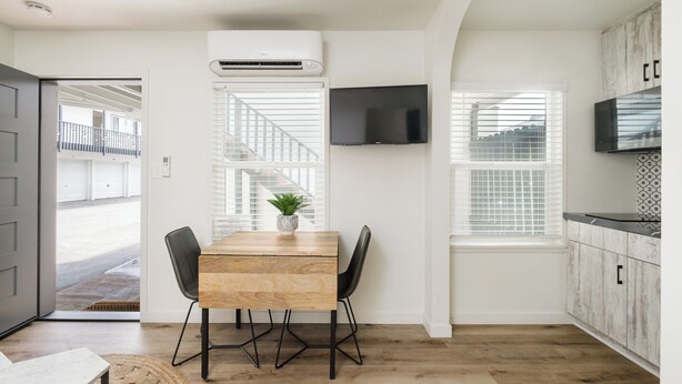 A modern kitchen with a wooden table, black chairs, and a potted plant. - First Floor King Suite (101) (Oceanside)