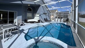 A covered outdoor swimming pool with lounge chairs and a seating area.