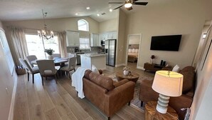 A spacious living area with a brown leather sofa, a round wooden coffee table, and a modern lamp. - Family Fun Fairway Villa (Haines City)