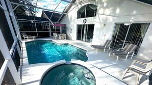 Une piscine avec un jacuzzi, des chaises longues et un patio couvert.