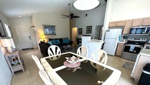 A compact living space with a dining area, kitchenette, and a ceiling fan.