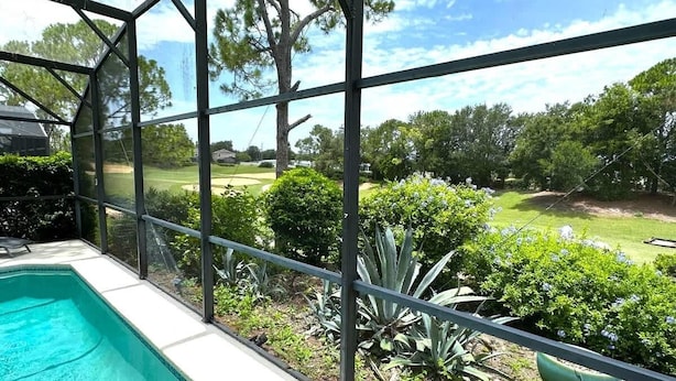 A swimming pool with a view of a well-maintained lawn and trees.