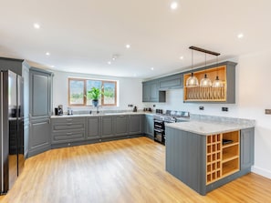 A modern kitchen with grey cabinetry, a wooden floor, a built-in oven, and a window with a view. - 5 bedroom accommodation in Belper (Belper)