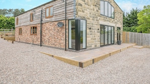 A two-story stone building with a gravel driveway and a wooden fence. - 5 bedroom accommodation in Belper (Belper)