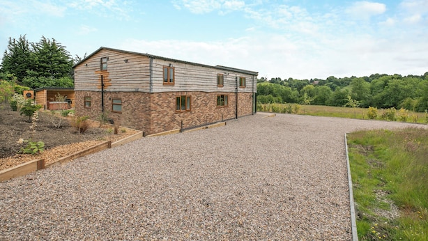 A two-story building with a gravel driveway and a fenced garden area. - 5 bedroom accommodation in Belper (Belper)