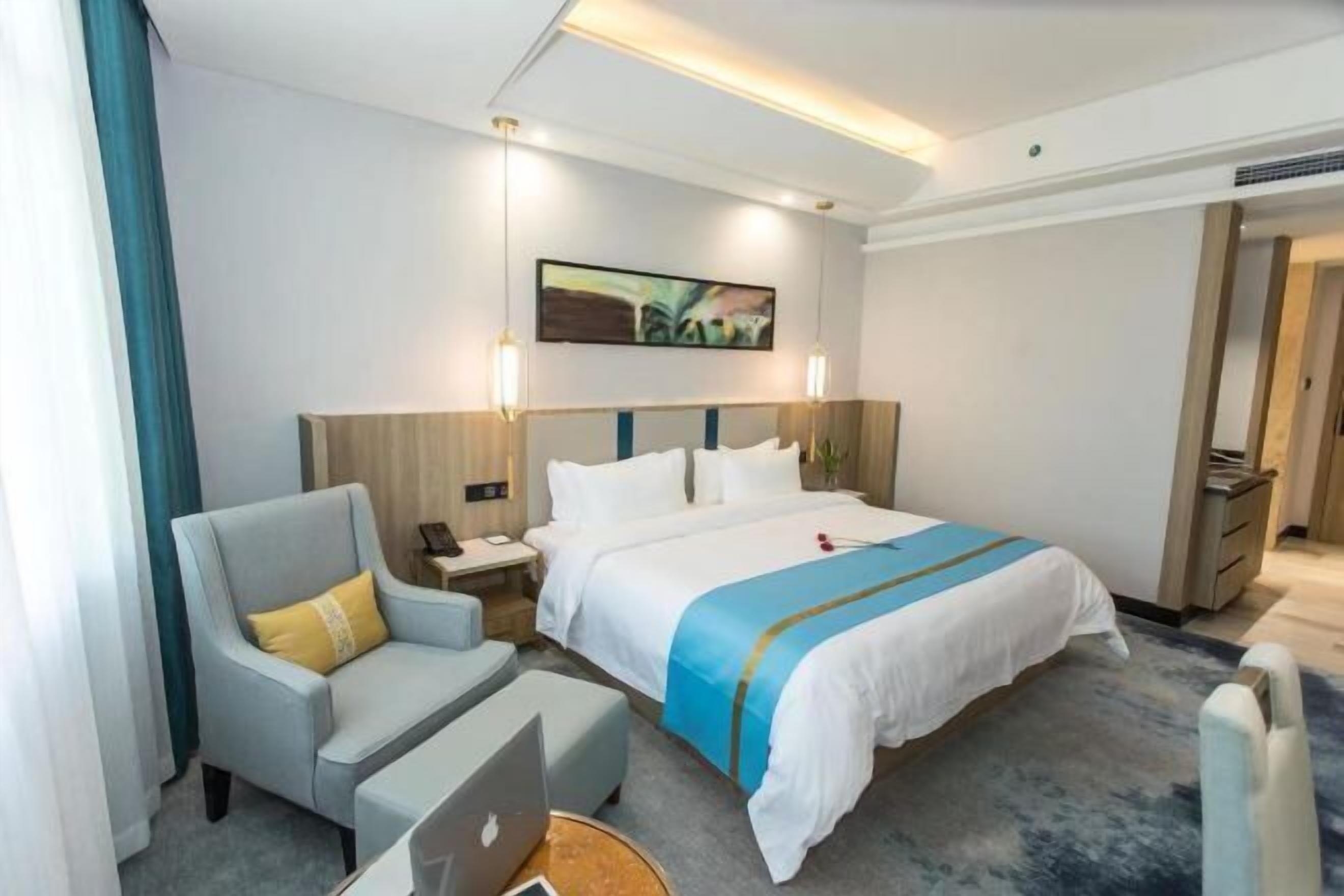 Een hotelkamer met een bed, een bureau, een stoel en een laptop.