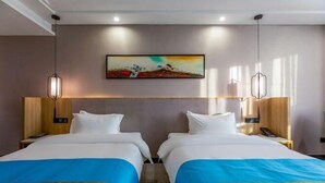 Habitación de hotel con dos camas, un cuadro en la pared y lámparas colgantes.