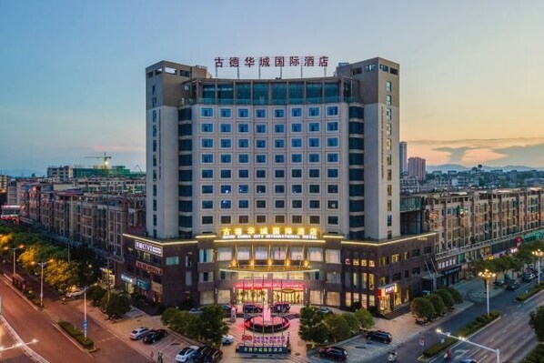 Un hotel de varios pisos con una entrada central, rodeado de otros edificios.