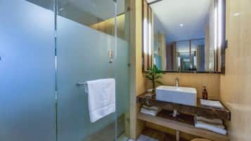 A modern bathroom with a glass shower enclosure, a wooden vanity, and a large mirror.