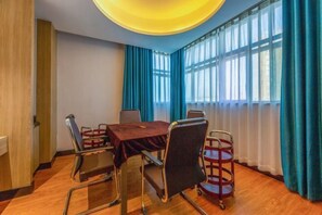 A conference room with a round table, four chairs, a red tablecloth, and a ceiling light fixture.