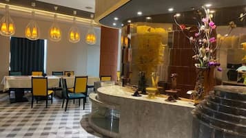 A hotel lobby with a check-in counter, seating area, and decorative plants.