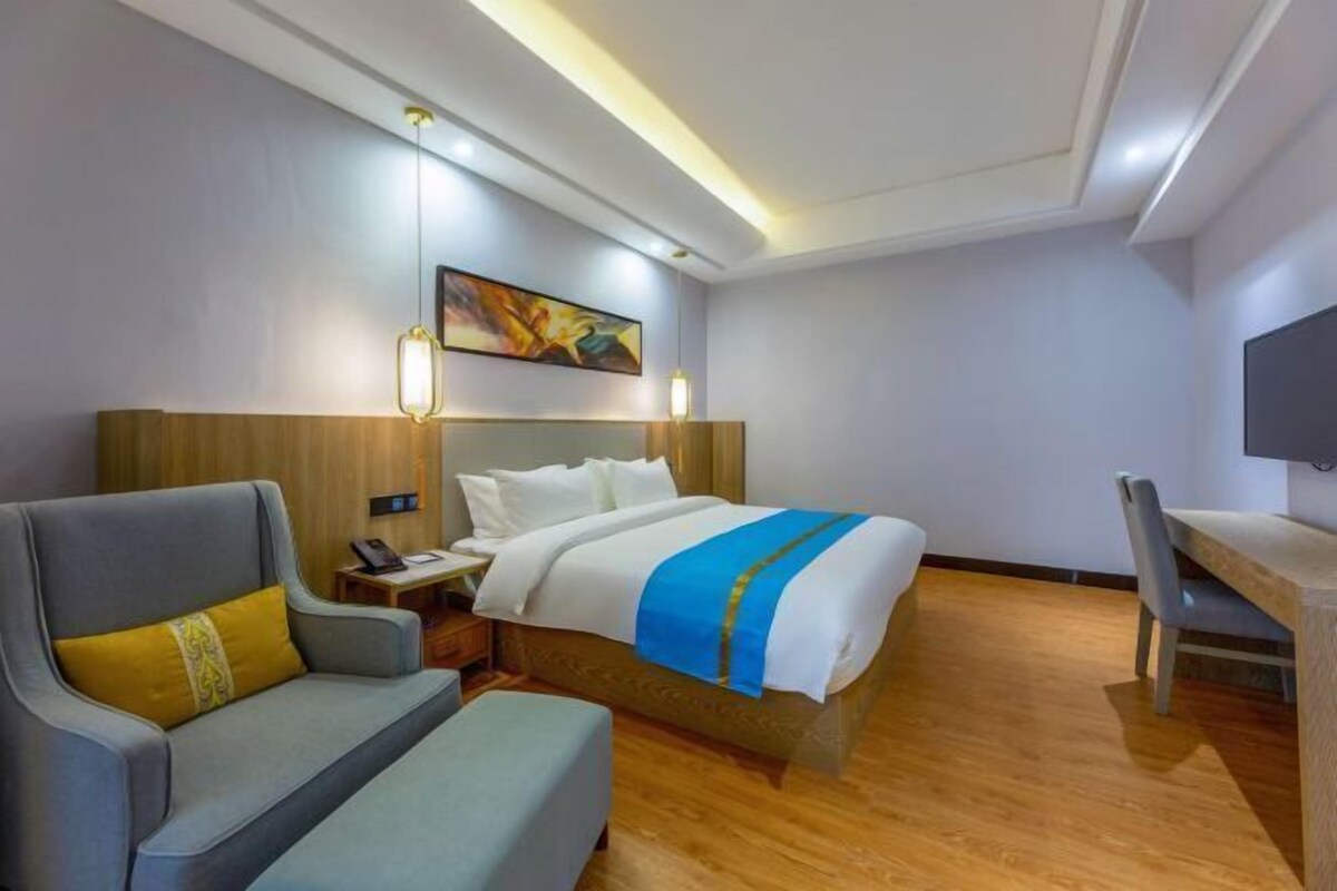 Una habitación de hotel con una cama, un sofá, un escritorio y un cuadro en la pared.