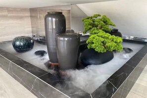 Un área de spa con un jacuzzi rodeado de jarrones grandes y una planta en maceta.