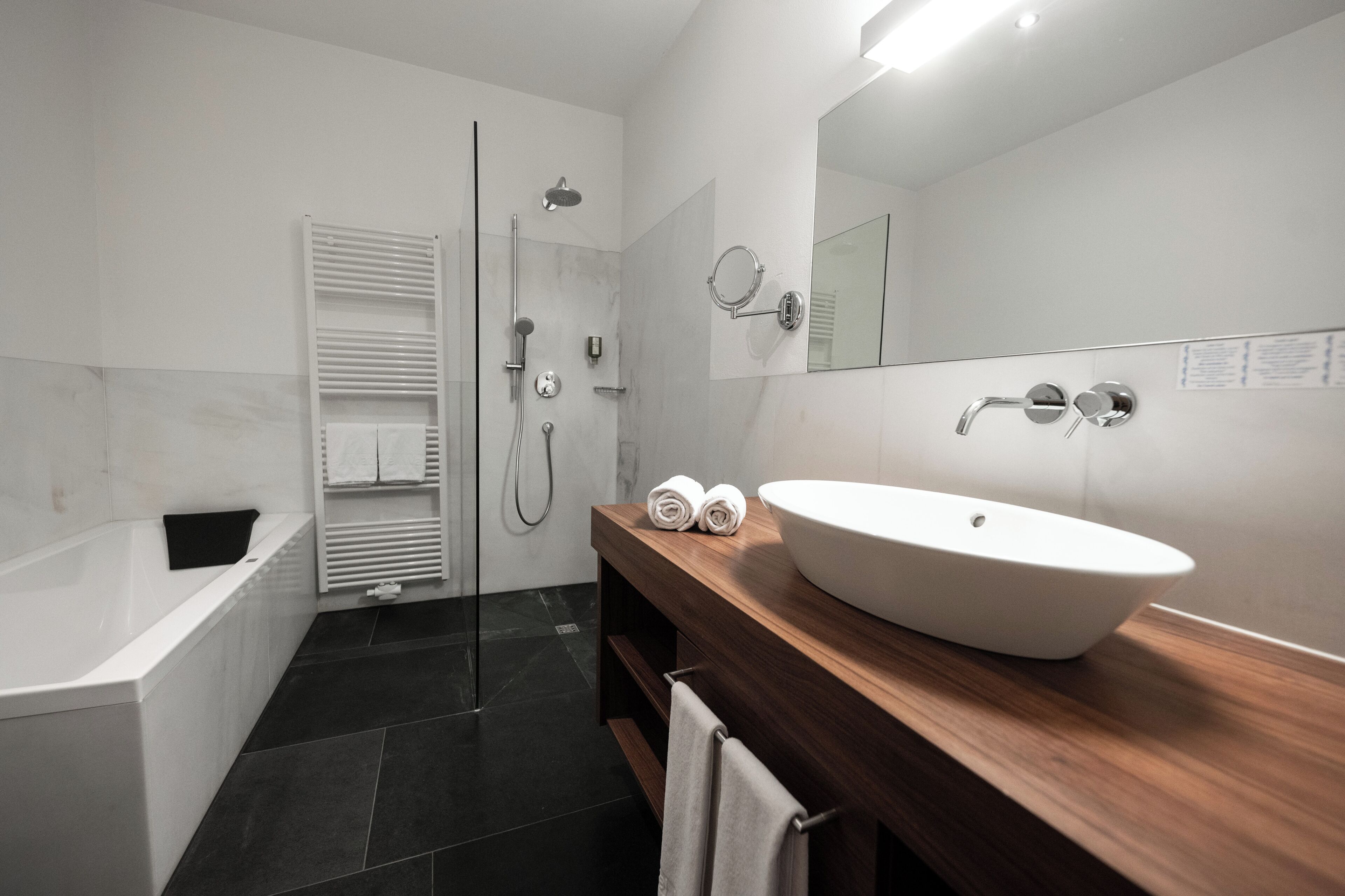 Un baño moderno con bañera, lavabo grande, espejo y zona de ducha.
