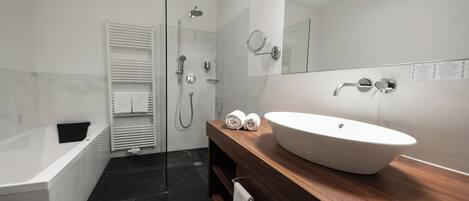 Un baño moderno con bañera, lavabo grande, espejo y zona de ducha.