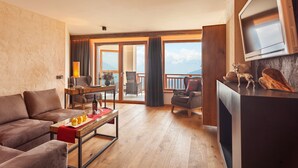 A modern living room with a sofa, coffee table, and a TV mounted on the wall. - Panoramahotel Watles (Malles Venosta)