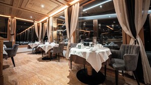 A restaurant with wooden ceiling, large windows, and tables set for dining. - Panoramahotel Watles (Malles Venosta)