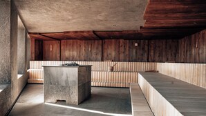 A modern interior with a stone bench, wooden panel walls, and a tiled floor. - Panoramahotel Watles (Malles Venosta)