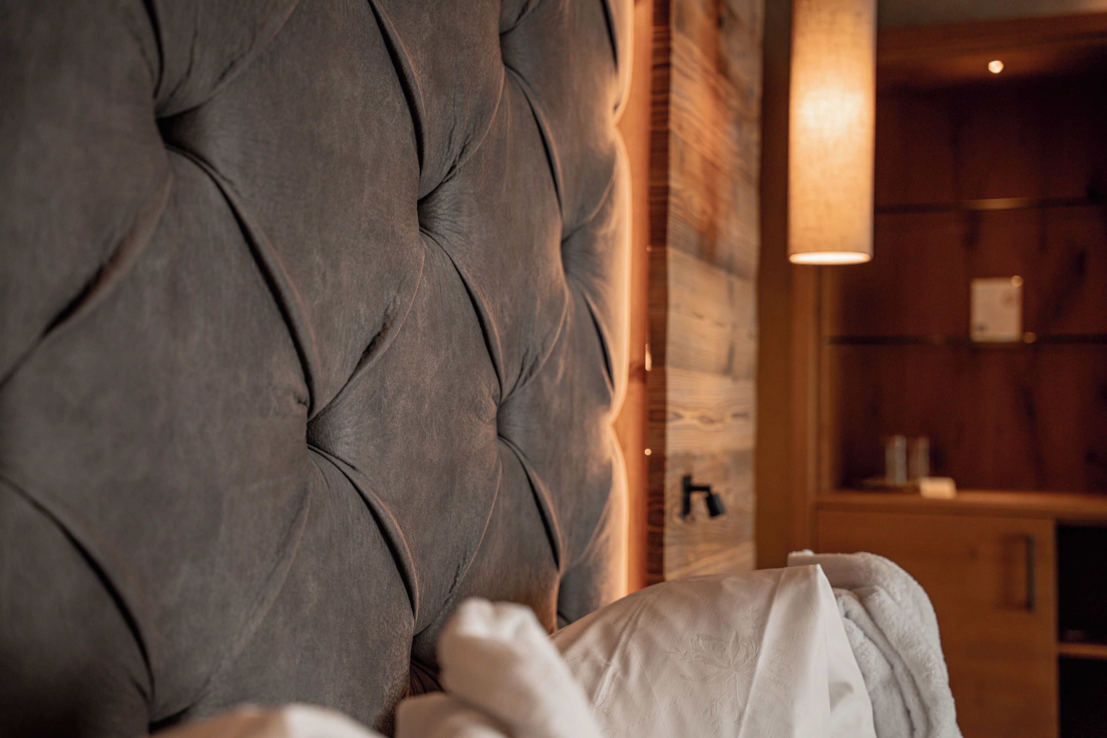 Une tête de lit capitonnée, un mur en bois et une étagère avec des objets.
