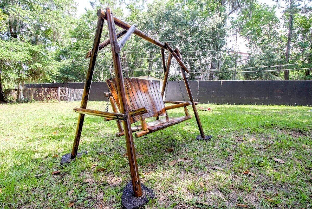 A wooden swing set in a grassy area with trees in the background.