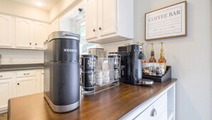Une cuisine équipée d’une machine à café Keurig, d’un espace dédié à la préparation du café et d’un panneau indiquant « bar à café ».