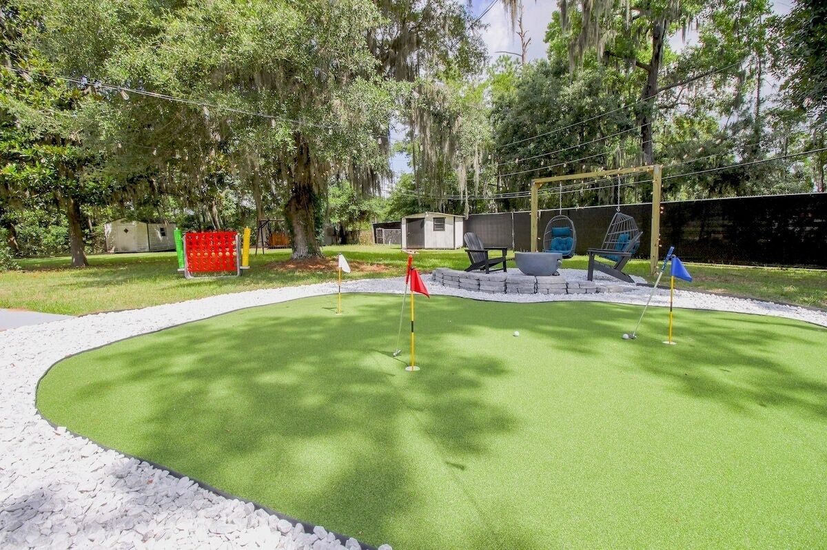 Een minigolfbaan met een putting green, zandbunkers en een klein gebouw op de achtergrond.