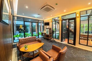 Un hall de hotel con un área de descanso, televisor y vistas al exterior.