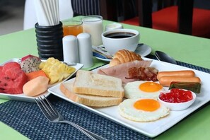 A breakfast plate with eggs, toast, bacon, sausage, and fruit. - J4 Samui Hotel (Koh Samui)