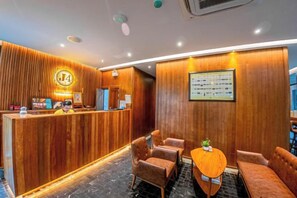 Un'area reception di un hotel con una scrivania in legno, posti a sedere e un menù incorniciato appeso al muro.