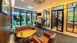 A modern interior with leather seating, a wooden table, and large windows offering views of greenery. - J4 Samui Hotel (Koh Samui)