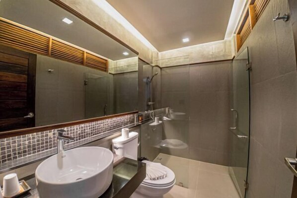 A modern bathroom with a large sink, toilet, and glass-enclosed shower. - J4 Samui Hotel (Koh Samui)