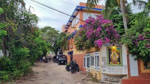 Un edificio con fachada colorida, un sendero de tierra y vehículos estacionados.