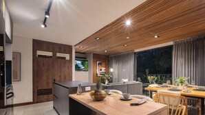 Eine moderne Küche mit Essbereich, Holzboden und einem großen Fenster mit Vorhängen.