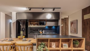 Eine moderne Küche mit einer zentralen Kochinsel, Edelstahlgeräten und einem Essbereich mit Holztischen und einem Tisch.