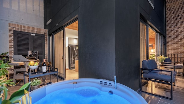 Ein Whirlpool in moderner Außenanlage mit Ziegelwand, Grill und Gartenmöbeln.