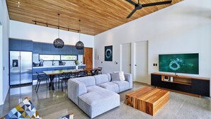 A modern living room with a sectional sofa, wooden coffee table, and a TV on a black entertainment unit. - Villa Alba (Cóbano)